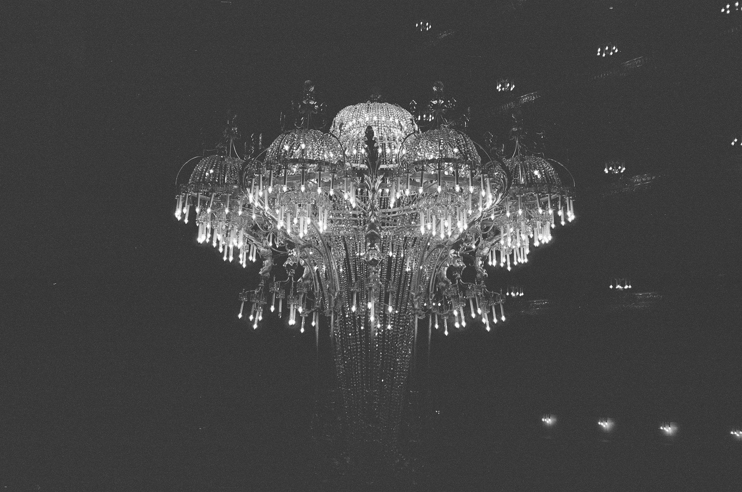 A crystal chandelier glowing against a dark ceiling