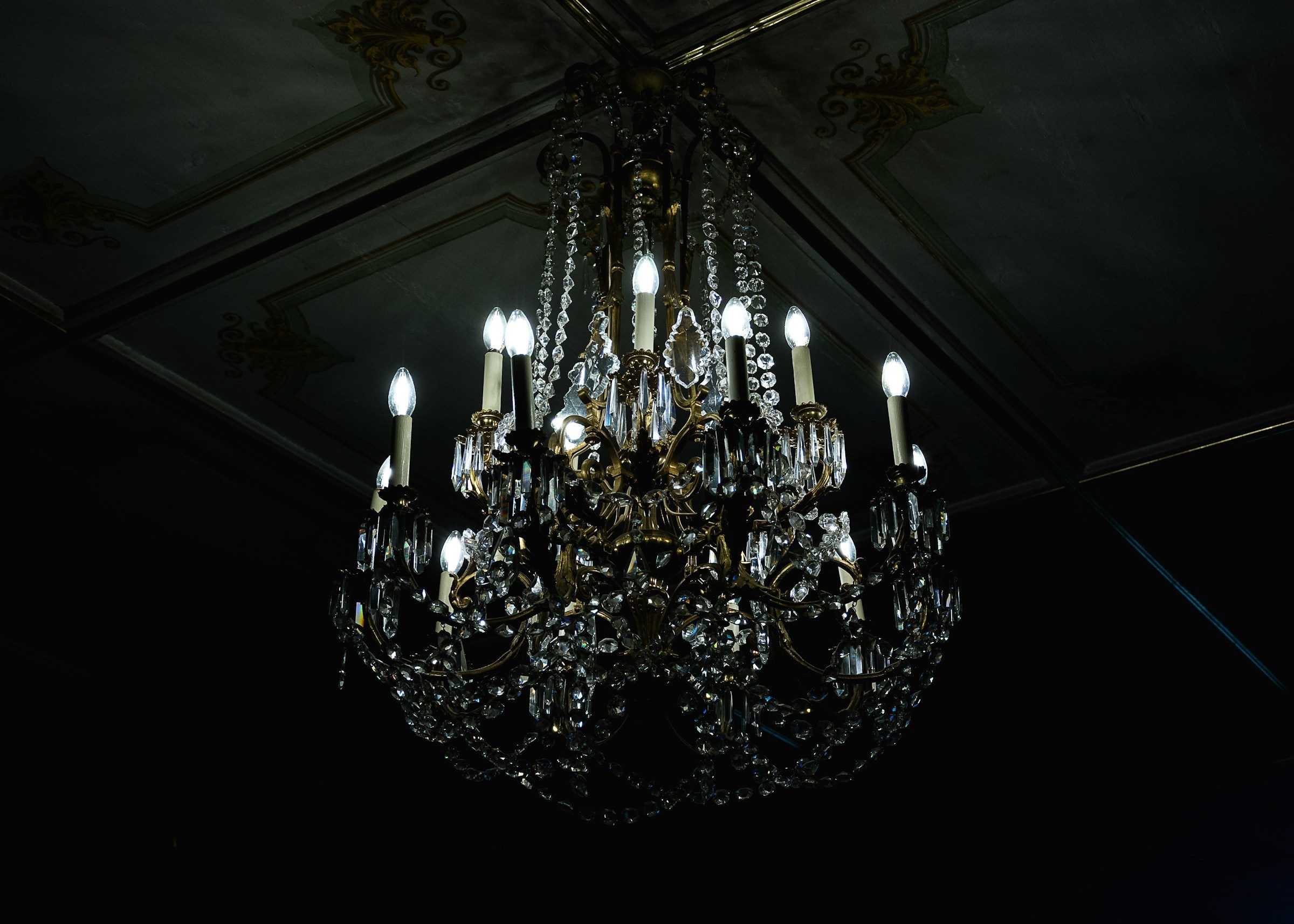 A candle-style chandelier lit in a darkened room