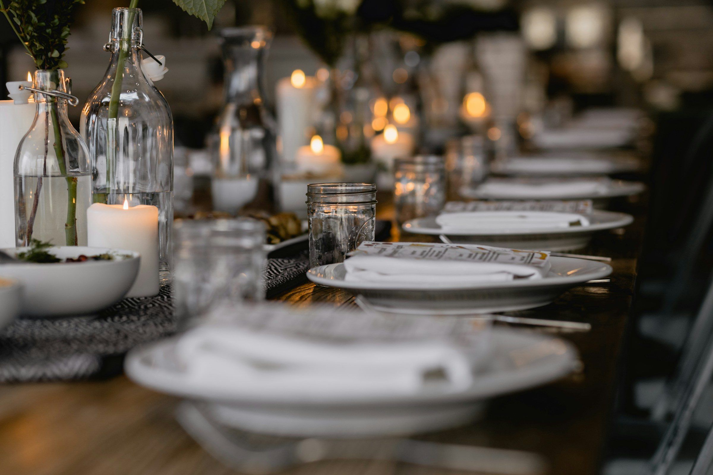 A long dinner table set with candles, glassware and fine plates