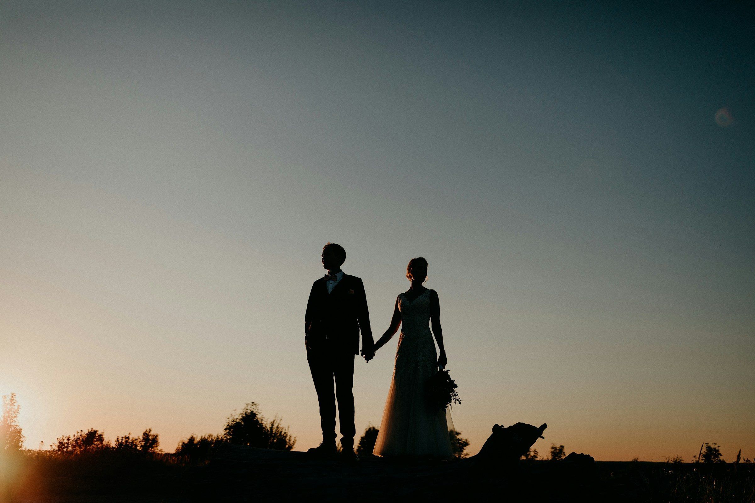 A couple walking hand in hand in silhouette at sunset