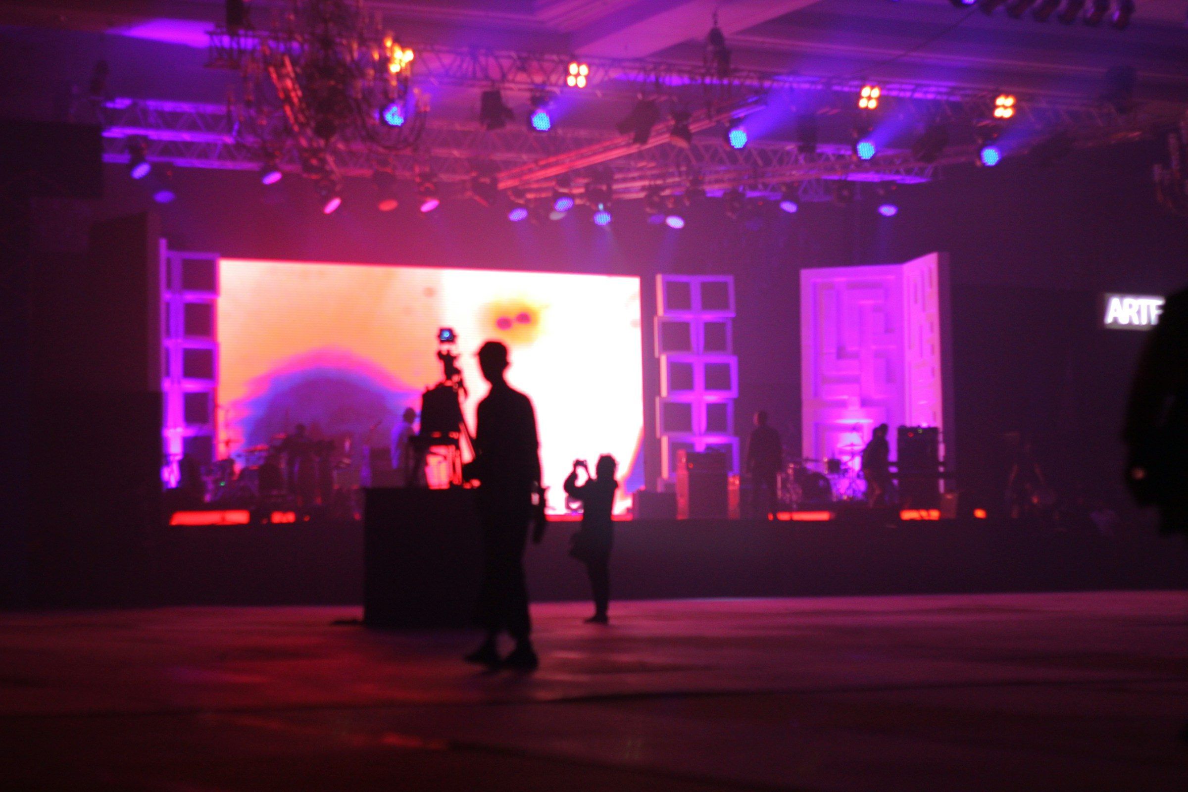 A stage with a glowing screen and violet lighting