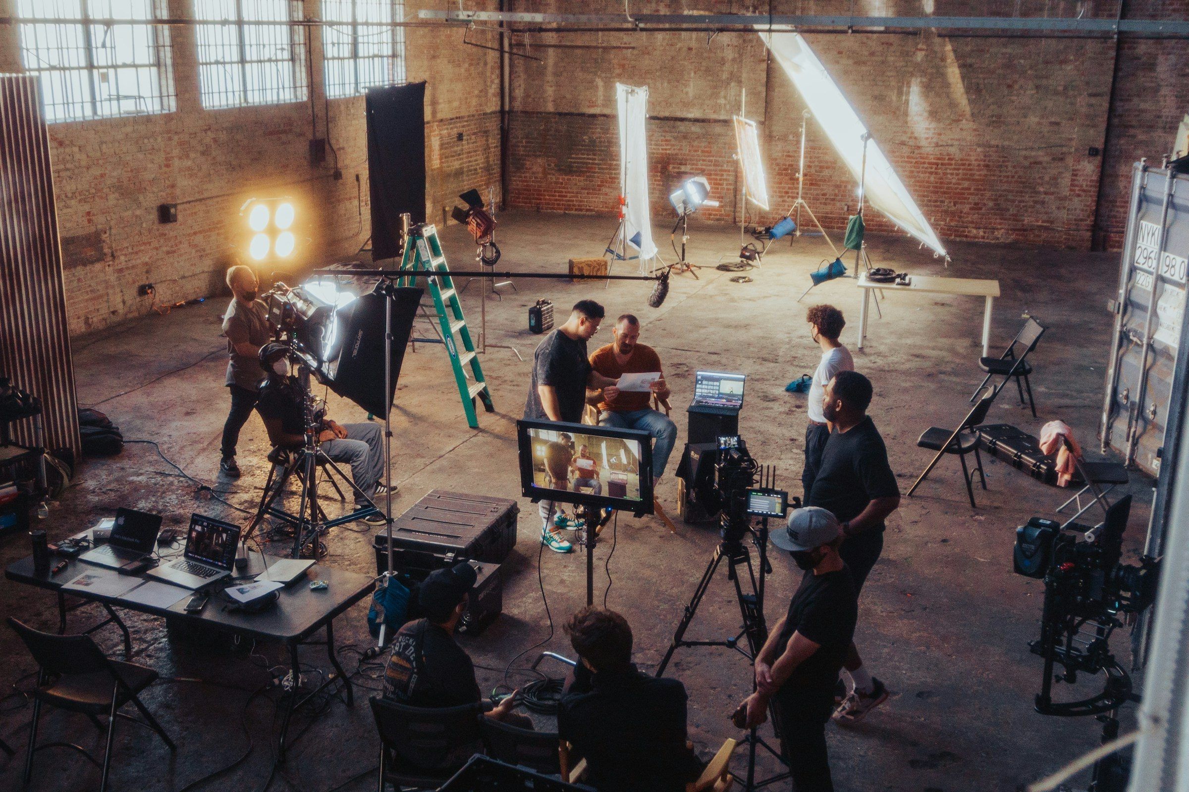 A production crew preparing lighting and cameras in a brick hall