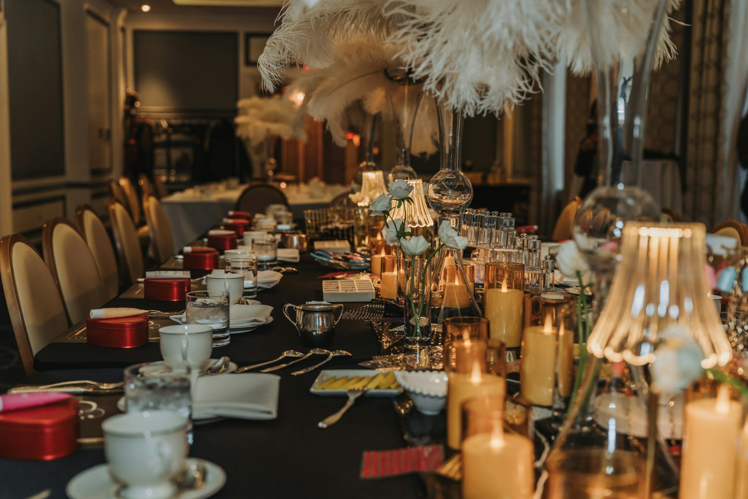 A candlelit tablescape with teacups and feather centrepieces