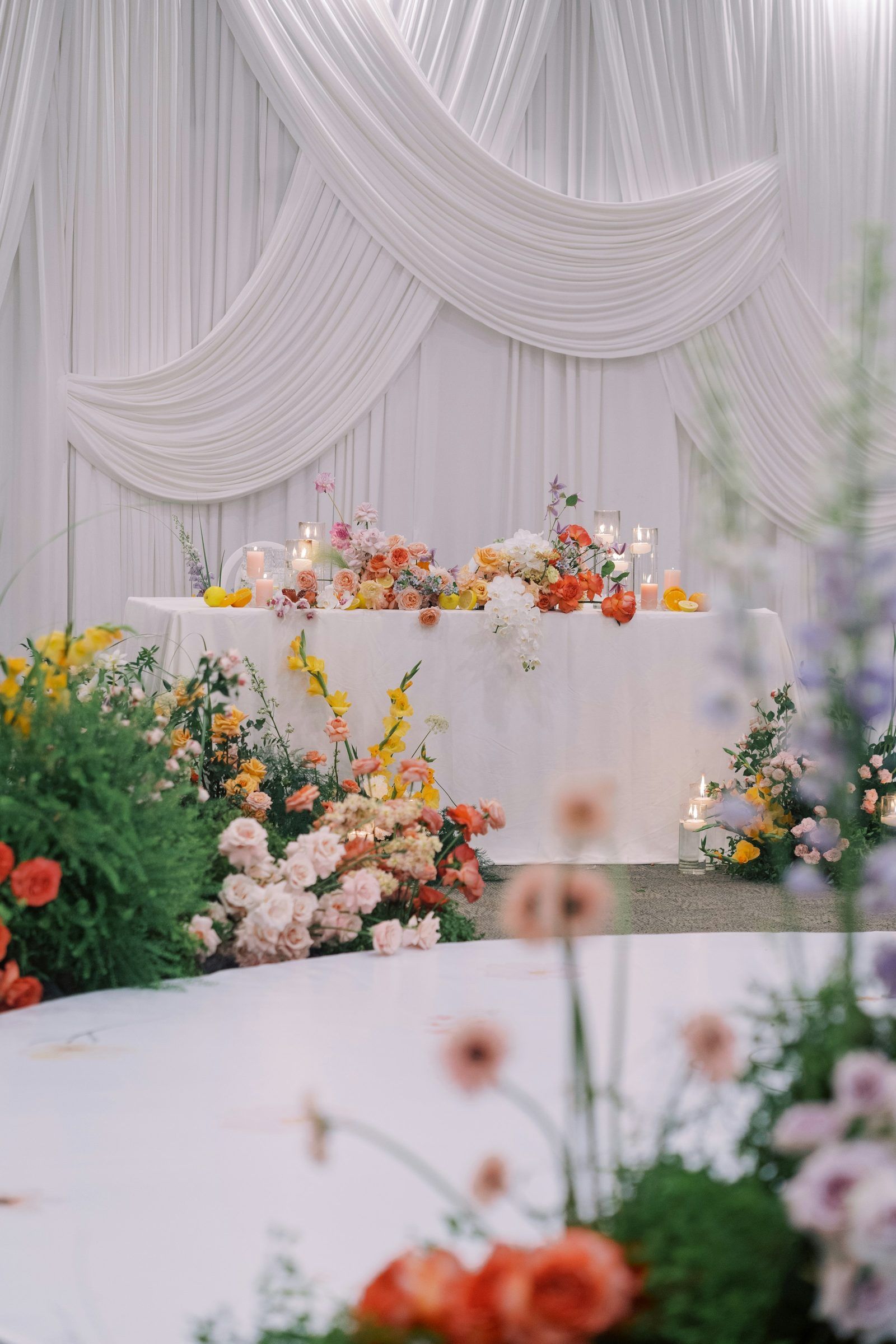 A draped white backdrop with a floral sweetheart table