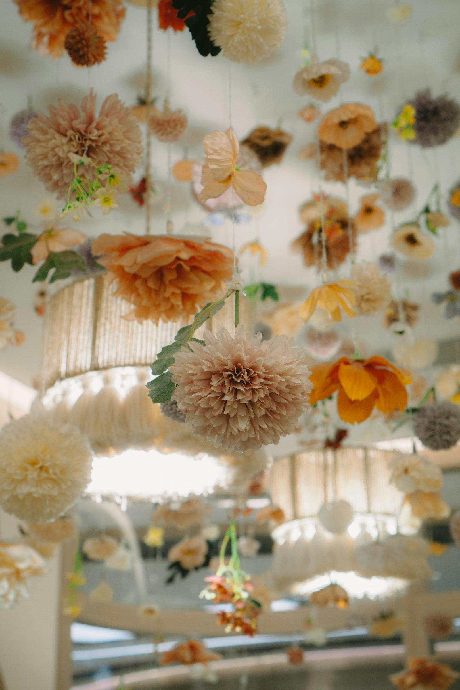 A canopy of peach and cream blossoms hanging above woven lampshades